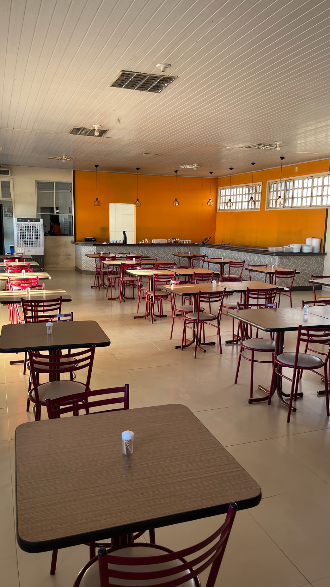 Salão interno com buffet e balcão de atendimento em parede laranja