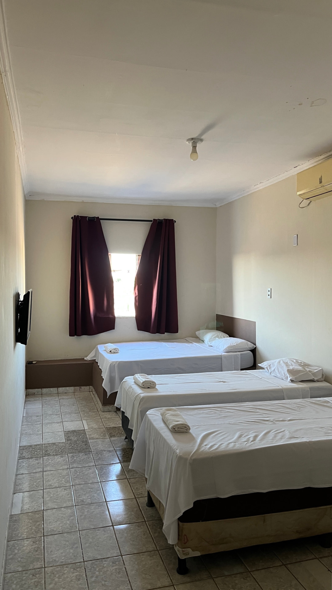 Quarto da pousada com três camas, ar-condicionado e TV